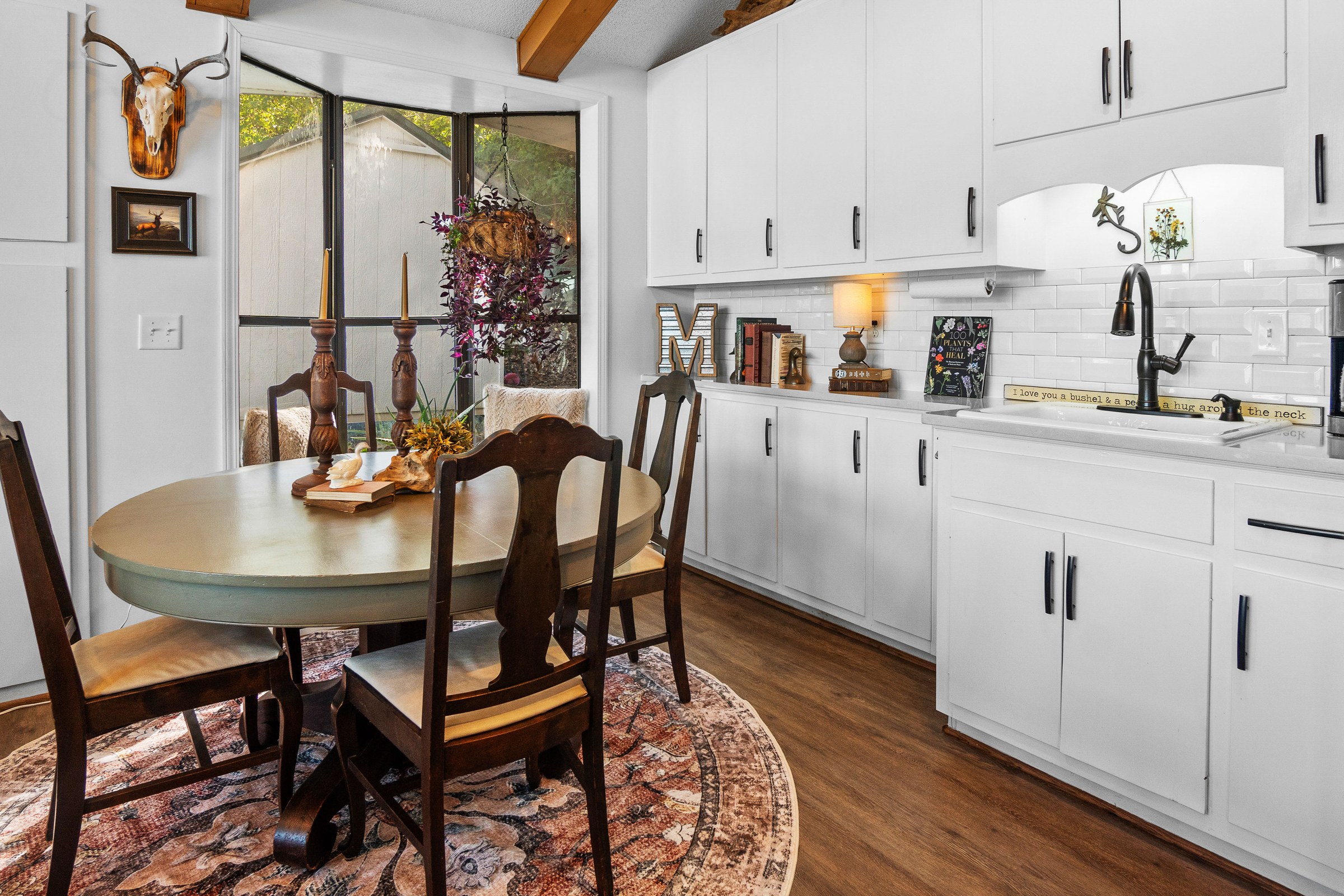 Round dining table on a patterned rug beside white cabinetry and a wall of lake-facing windows